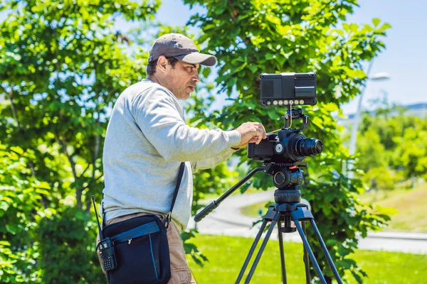 Un caméraman professionnel prépare une caméra et un trépied avant de tirer — Photo