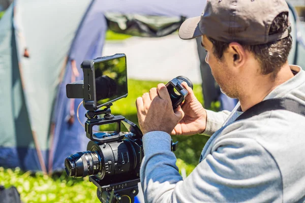 Um cameraman profissional prepara uma câmera e um tripé antes de atirar — Fotografia de Stock
