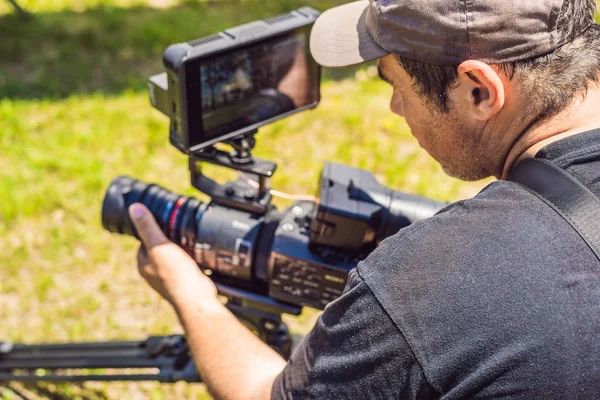 Um cameraman profissional prepara uma câmera e um tripé antes de atirar — Fotografia de Stock