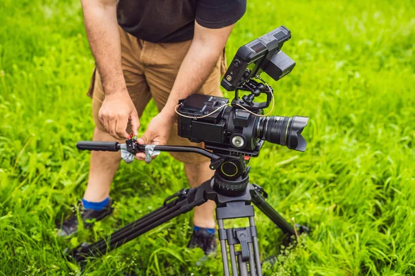 Un camarógrafo profesional prepara una cámara y un trípode antes de disparar —  Fotos de Stock