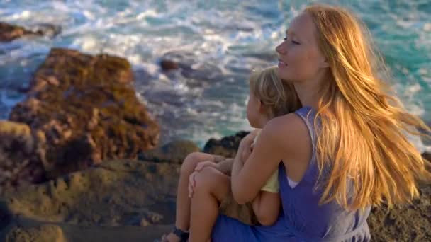 母とタナロット寺院の近くに海の波を見ている岩の上に座って息子のスローモーション撮影 — ストック動画