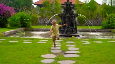 Bali Adası'Çeşme Taman Ayun Tapınağı'nda çalışan küçük bir çocuk bardak Slowmotion