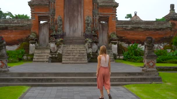 Toma en cámara lenta de una joven mujer caminando alrededor del templo Taman Ayun en la isla de Bali — Vídeos de Stock