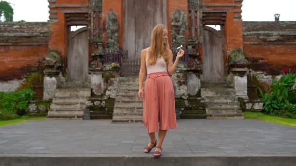 Toma en cámara lenta de una joven mujer caminando alrededor del templo Taman Ayun en la isla de Bali — Vídeo de stock