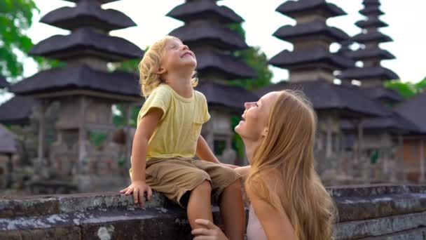 Zeitlupenaufnahme einer jungen Frau und ihres Sohnes, die um den Taman Ayun Tempel auf der Bali-Insel gehen — Stockvideo