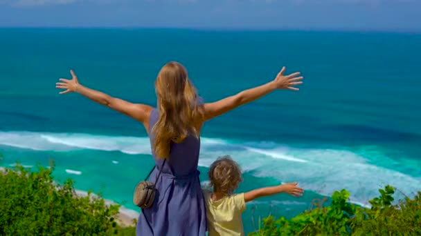 Slowmotion lövés egy fiatal nő és a fia áll a szélén a szikla, nézte az óceánt. Suluban és Anna Anna helyére. Utazótáska-val kids koncepció — Stock videók