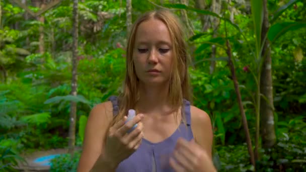 Mujer joven en bosque tropical aplica aerosol de mosquitos en la piel — Vídeos de Stock