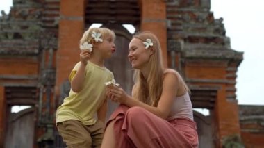 Genç bir kadın ve oğlu Bali Adası Taman Ayun Tapınağı merdivenlerde oturan el atış.