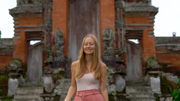 Toma en cámara lenta de una joven mujer caminando alrededor del templo Taman Ayun en la isla de Bali — Vídeos de Stock