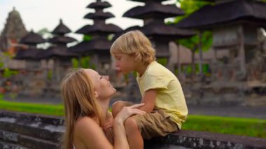 Genç bir kadın ve oğlu Bali Adası'Taman Ayun tapınağın yürüyüş Slowmotion atış