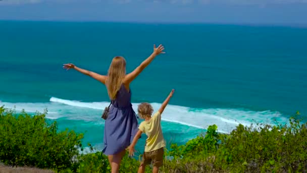 若い女性と彼女の息子は、海を眺める崖の端に立ってのスローモーション撮影。Suluban、Nyang Nyang 場所です。子供概念と一緒に旅行 — ストック動画