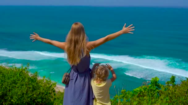Slowmotion lövés egy fiatal nő és a fia áll a szélén a szikla, nézte az óceánt. Suluban és Anna Anna helyére. Utazótáska-val kids koncepció — Stock videók