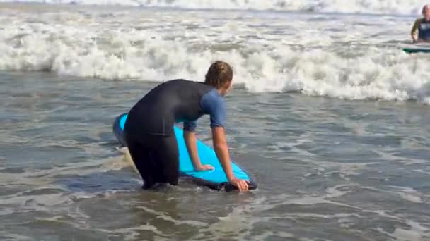 Bali, Indonezja - maja. 12: Slowmotion strzał młodej kobiety na lekcji szkolenia surfing, zmaga się z fal — Wideo stockowe