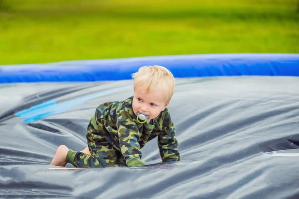 Маленький мальчик наслаждается прыжками на батуте летний день снаружи — стоковое фото