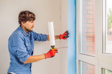 Pencere montaj için güç aracını kullanarak bir mavi tişörtlü adam.