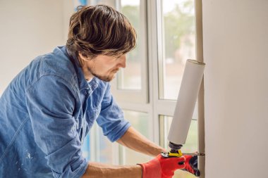 Mavi gömlekli köpük güç aracı pencere montaj sırasında kullanarak genç tamirci.