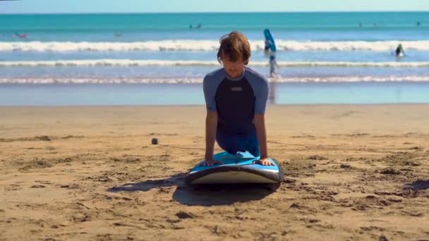 Genç adam bir plajda sörf eğitimi alarak — Stok video