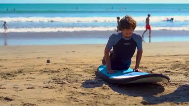 Joven tomando un entrenamiento de surf en una playa — Vídeos de Stock