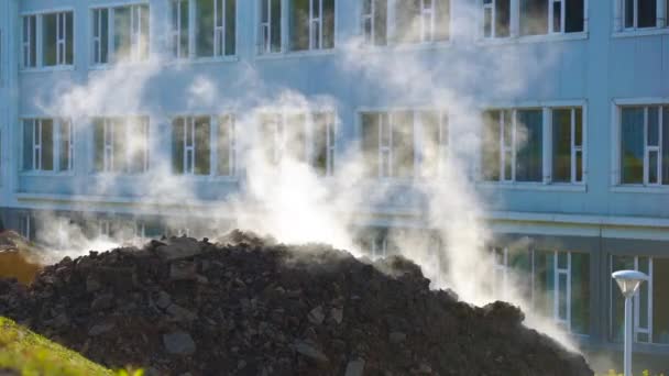 Konzept des Durchbruchs der unterirdischen Versorgungsunternehmen. Dampf dringt aus dem Boden. Bagger gräbt ein Loch, um die Lage des Durchbruchs der Heizzentrale zu bestimmen. Zeitlupenschuss — Stockvideo