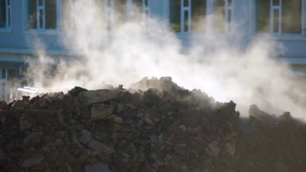 Concept de percée des services publics souterrains. la vapeur s'échappe du sol. Pelle creuse un trou pour déterminer l'emplacement de la percée de la principale de chauffage. Coup de ralenti — Video