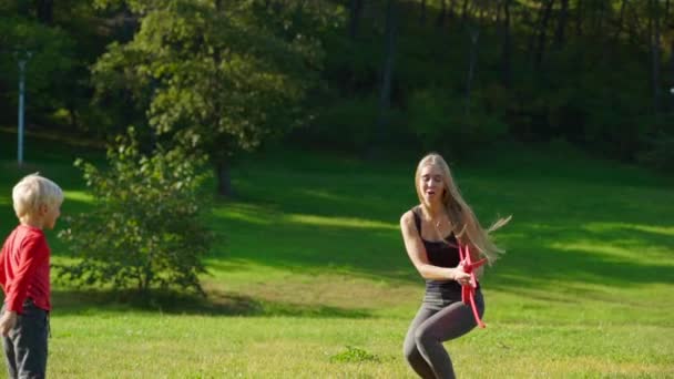 Slowmotion shot of a young woman and her little son play with an airplane on a lawn — Stock Video