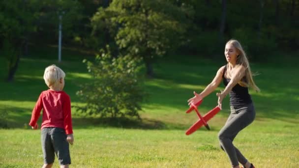 Slowmotion shot of a young woman and her little son play with an airplane on a lawn — Stock Video