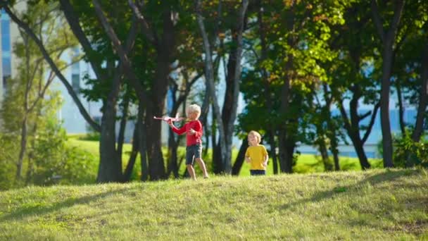 Slowmotion zastřelil dva malí chlapci hrají s letadlem na trávníku — Stock video