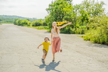 Mutlu anne ve oğlu oyuncak uçak eski pist arka plan karşı oynamaktan. Çocuklar kavramı ile seyahat.