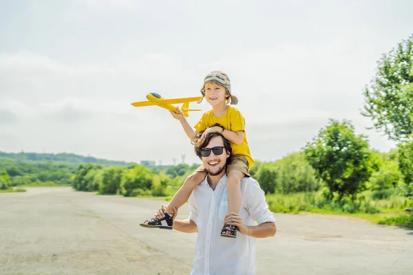 Happy father and son playing with toy airplane against old runway background. Traveling with kids concept.