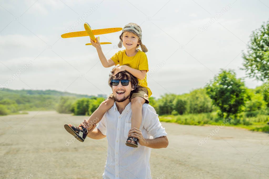 Happy father and son playing with toy airplane against old runway background. Traveling with kids concept.