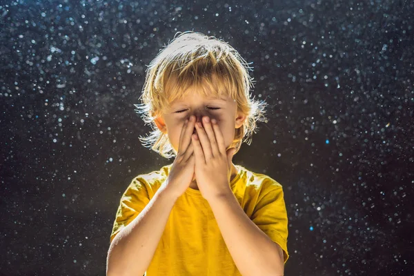 Allergy to dust. Boy sneezes because he is allergic to dust. Dust flies in the air backlit by light