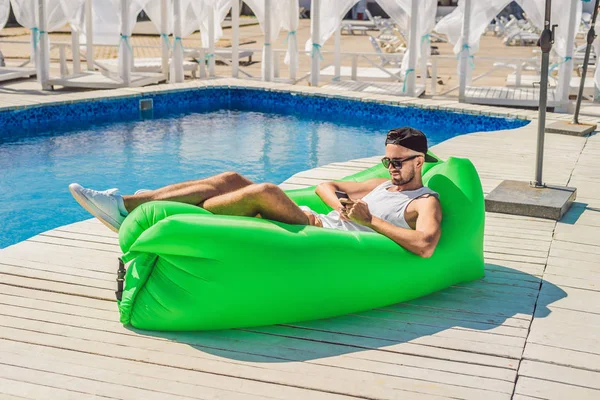 Joven disfrutando del ocio, acostado en el sofá de aire Lamzac, cerca de la piscina —  Fotos de Stock