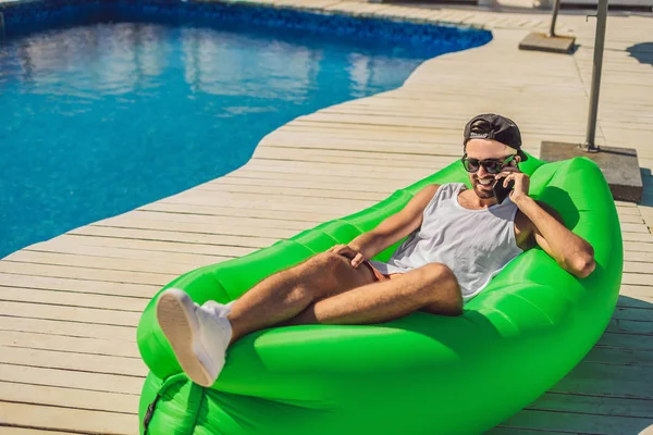 Young man enjoying leisure, lying on the air sofa Lamzac, near the pool — Stock Photo, Image