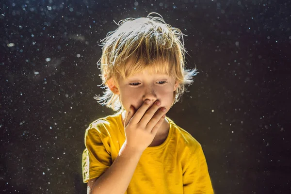 Alergia al polvo. El chico estornuda porque es alérgico al polvo. El polvo vuela en el aire retroiluminado por la luz — Foto de Stock