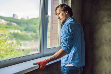 Man in a blue shirt doing window installation. clipart