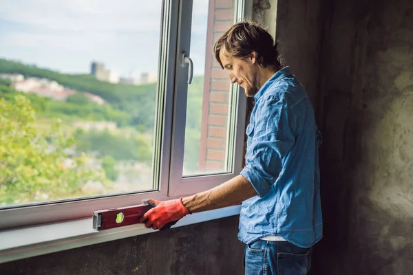 Crafty man in blue shirt doing window installation.