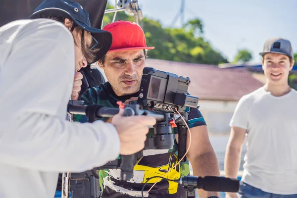 Operador Steadicam y su asistente preparan cámara y estabilizador-cardán de 3 ejes para un rodaje comercial —  Fotos de Stock