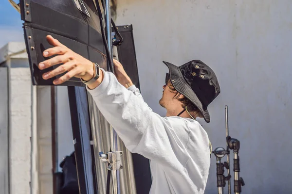 El gaffer o el electricista jefe en una unidad de producción cinematográfica o televisiva instala las luces y el soporte luminoso en un rodaje comercial — Foto de Stock