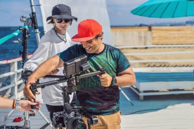 ticari bir klip çekimi üretim takımında. Steadicam Operatörü 3 eksenli kamera Sabitleyici ve sinema-grade kamera kullanır