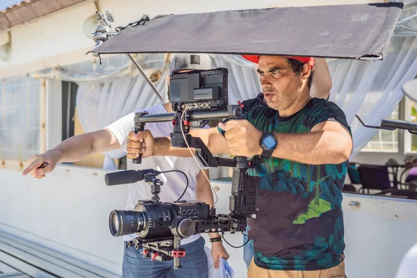 Il team di produzione per un servizio video commerciale. L'operatore Steadicam utilizza lo stabilizzatore della fotocamera a 3 assi e la fotocamera di livello cinematografico — Foto Stock