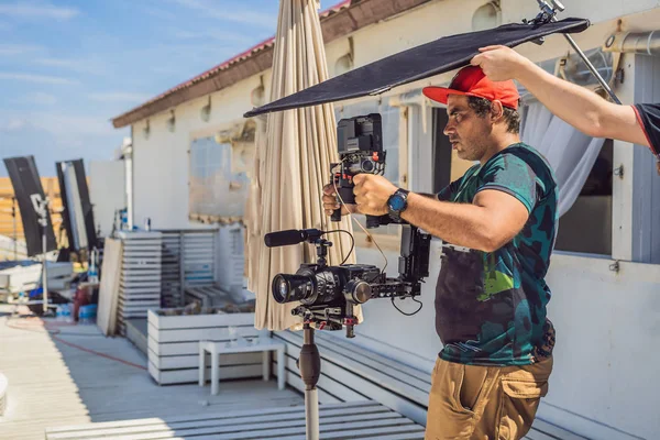 The production team on a commercial video shoot. Steadicam operator uses the 3-axis camera stabilizer and cinema-grade camera — Stock Photo, Image