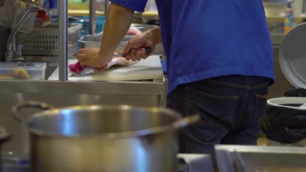 Steadicam skott av kocken på en japansk restaurang med öppet kök, styckning, förbereder en filé från en stor lax — Stockvideo