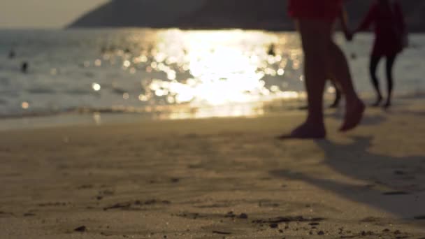 Blurred shot of a busy beach in tropics with silhouettes of people going by — Stock Video