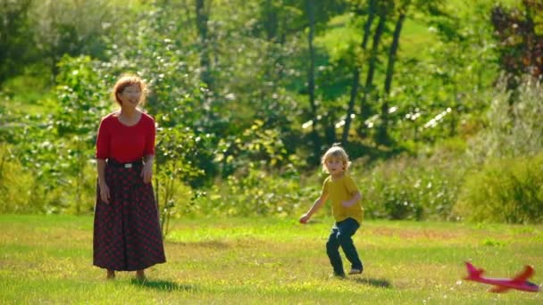 Slowmotion πλάνο του μια γιαγιά και εγγονός παίζει με ένα αεροπλάνο σε έναν χορτοτάπητα — Αρχείο Βίντεο