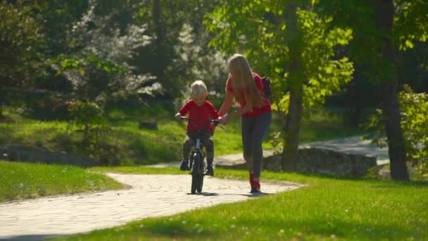 Lassú lövés, egy fiatal nő tanítani kis fiát, hogyan kell kerékpározni — Stock videók