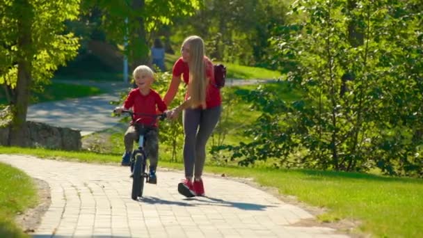 一个年轻女子的慢动作镜头教她的小儿子如何骑自行车 — 图库视频影像