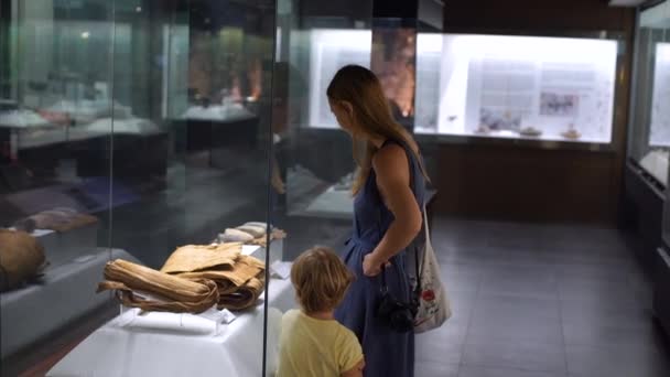 Мать и сын смотрят историческую экспозицию в музее естественной истории — стоковое видео