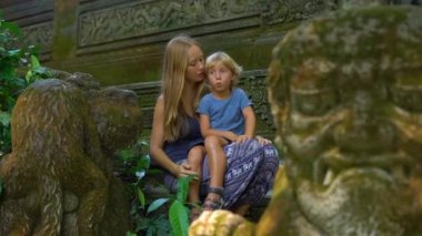 Genç bir adam ve küçük oğlu maymun orman Eko-Park Ubud, Endonezya merdivenlerde oturan ağır çekim çekim