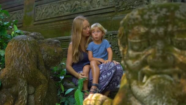 Filmagem em câmera lenta de um jovem e seu filho sentado nas escadas do parque ecológico da floresta de macacos em Ubud, Indonésia — Vídeo de Stock