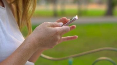Steadycam atış bir cep telefonu kullanan bir parkta oturan genç bir kadın